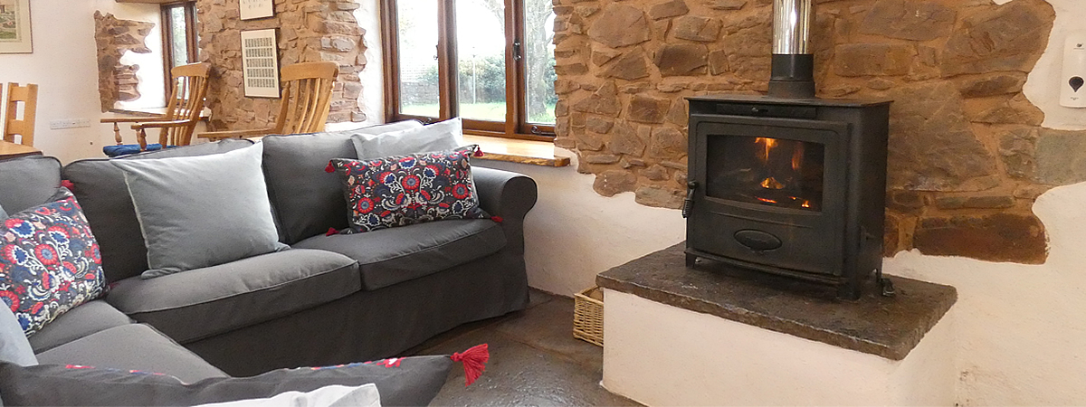 Cosy spacious corner sofa by the woodburner stove in The Hayloft